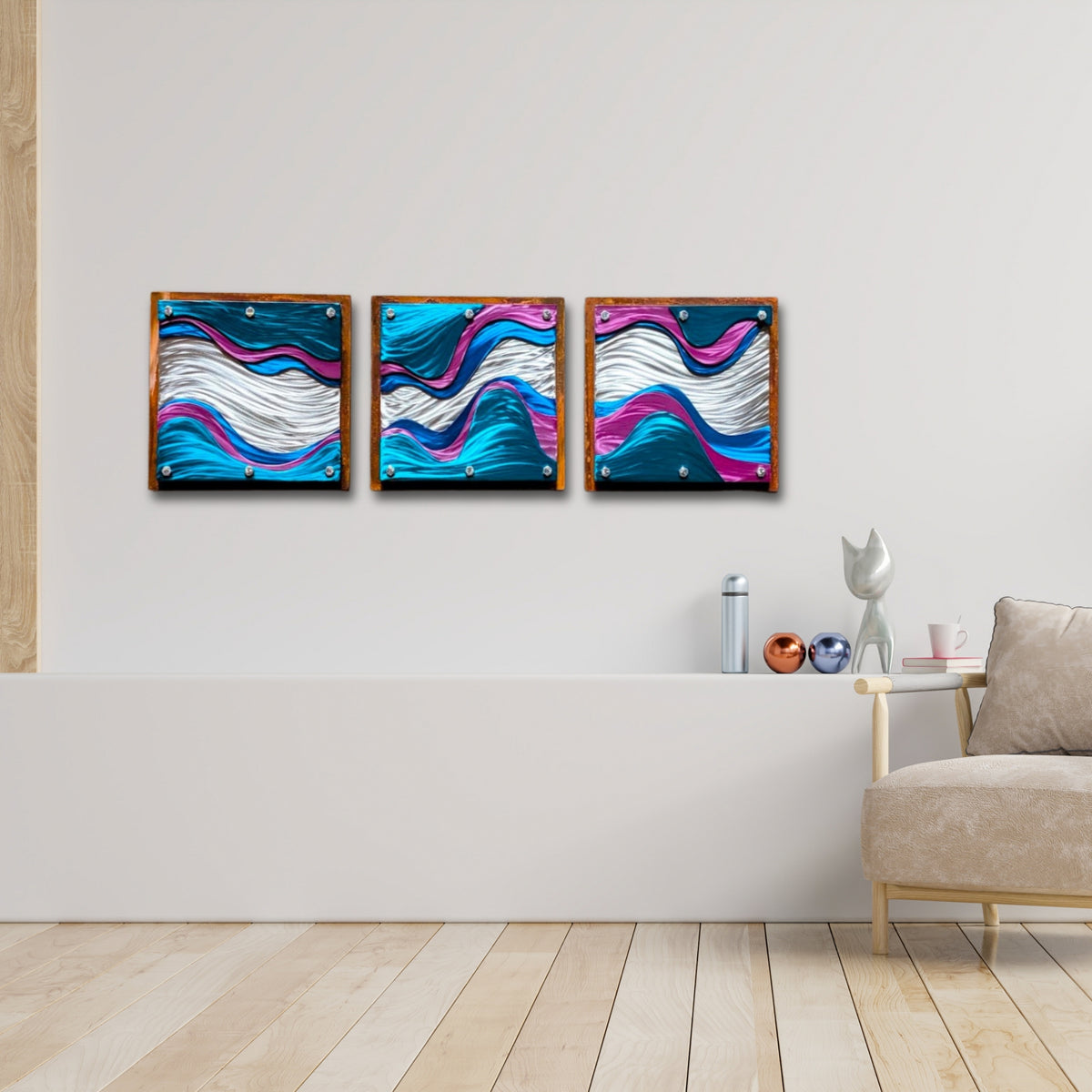 Three layered steel wave panels hung side by side in a row above a white ledge in a light, modern living room.