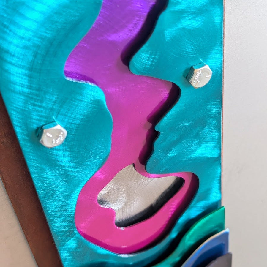 Detail of a teal steel panel with a magenta and purple river shape, a polished steel center, and visible hex bolts.