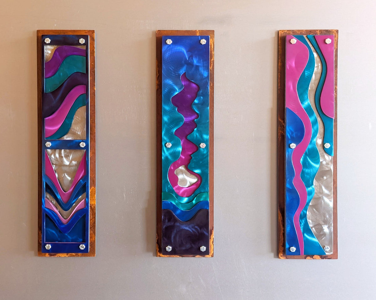 metal-abstract-wallart-blue (gray wall front view): Front view of Confluence, a set of three tall steel panels with flowing water shapes in pink, teal, purple, and blue on a rusted steel frame.
